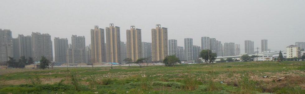 南京市建邺区河北村的八百亩棚改地块，已基本完成拆迁，部分土地平整覆绿（远景为商品房）