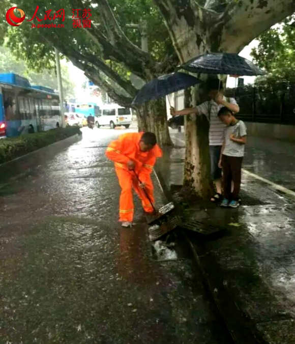 南京城管队员暴雨中徒手通管道 市民打伞相伴