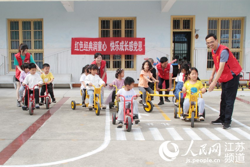 志願者陪孩子們戶外玩耍兒童小車。陳欣攝