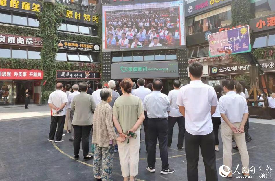 徐州中心商圈“彭城壹號”步行街室外LED大屏前市民駐足觀看慶祝大會直播。張毓攝