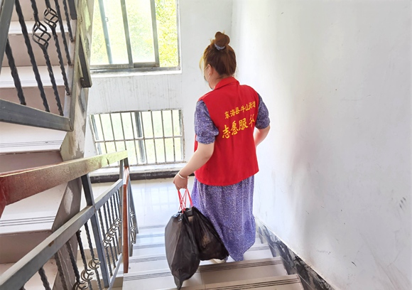 幸福居委会工作人员帮助居家隔离人员处理生活垃圾。东海县委宣传部供图