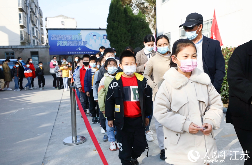 在淮安市淮安區，當地小學生在家長陪伴下排隊接種疫苗。趙啟瑞攝