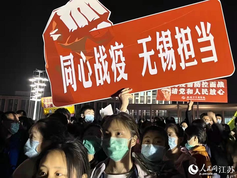 4月4日凌晨，出發上海前，一位醫護人員手舉“同心戰疫 無錫擔當”的手牌。無錫市委宣傳部供圖
