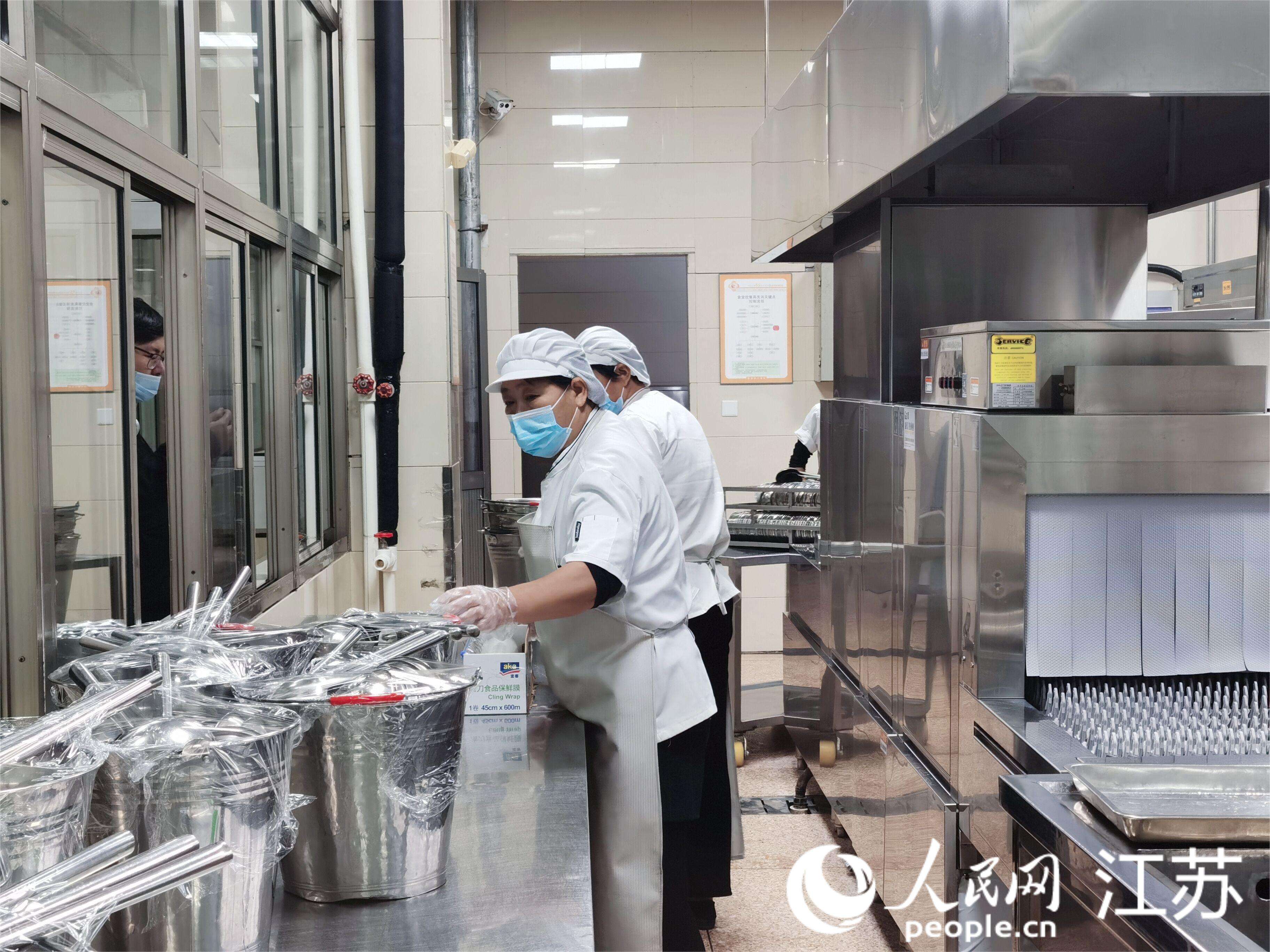 崇川学校食堂工作人员正在摆放已经严格消毒过的餐具。人民网记者王继亮摄