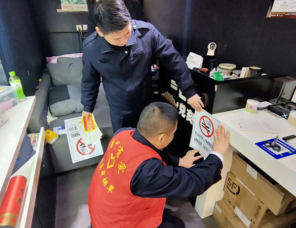 执法人员与志愿者在电子烟店张贴禁止向未成年人售烟标识。李菁菁摄 