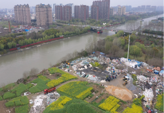 东台市通榆河东进大桥南侧，紧邻水体设置垃圾回收场，大量疑似工业固废露天堆放。