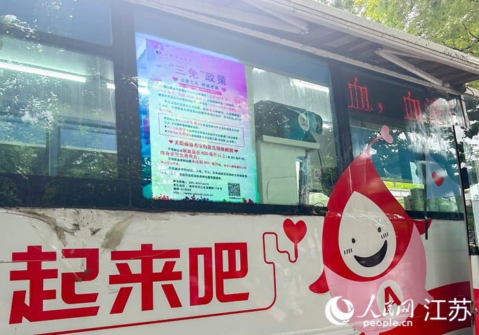 江苏省血液中心移动献血车身上的“三免”政策宣传。人民网 王丹丹摄