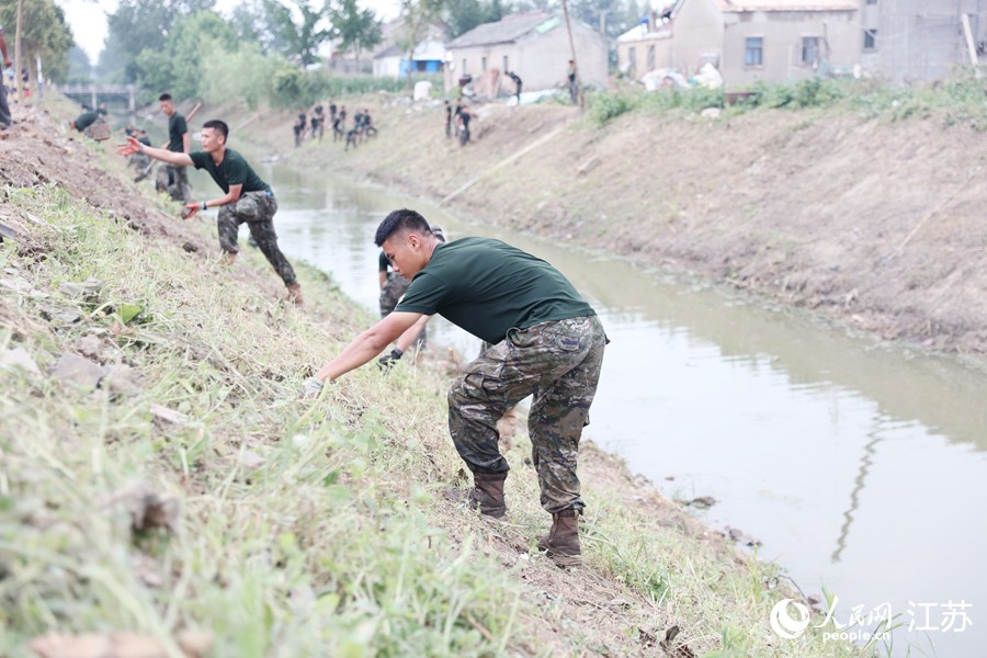 武警官兵幫助百姓清理河堤。人民網 余樂攝