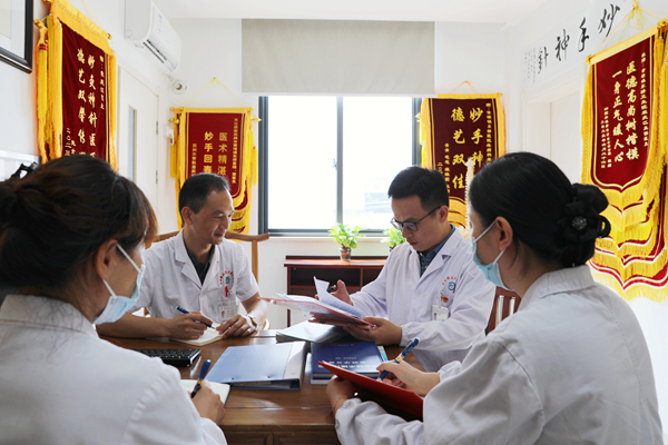  榮慶江（左二）和同事在研究患者病歷。黃埭鎮供圖
