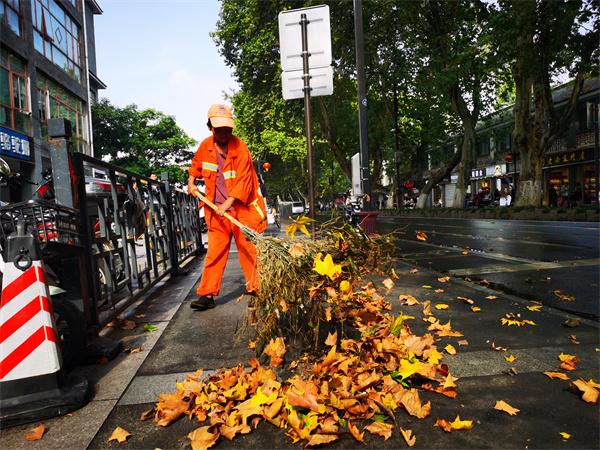 在南京夫子庙附近，一名环卫工人在清扫落叶。南京城管供图