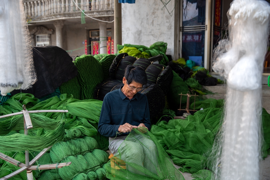 戴家村漁網編織生產基地內村民在手工編織漁網。周社根攝