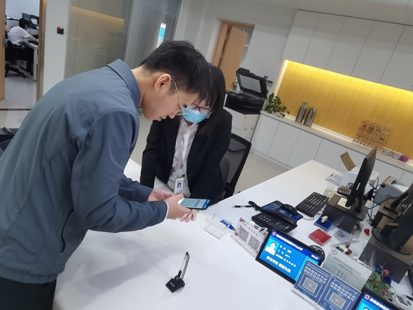工作人员指导公司员工手机查询企业档案。苏州高铁新城供图