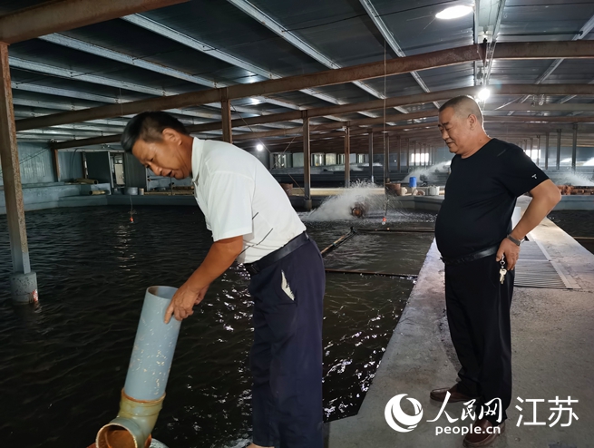 沈玉華（右）在溫室大棚內為村民講解鰻魚養殖過程中的細節。人民網記者王繼亮攝