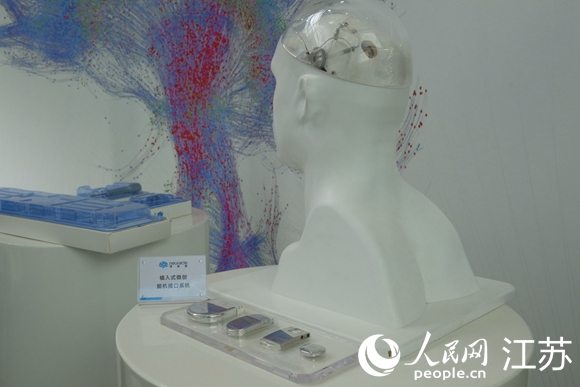 右为植入老杨脑中的“NEO微创式无线脑机接口系统”。人民网 王雪彤摄