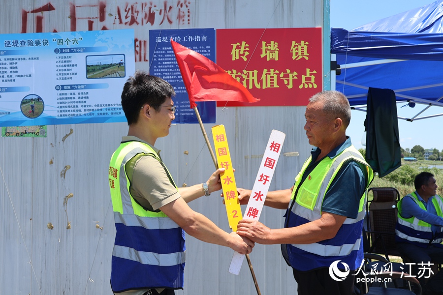 两个防汛值守点的巡堤人员交换“水牌”。人民网 杨维琼摄