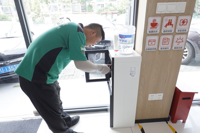 外賣騎手正在愛心驛站的飲水機前接水。楊斌 攝