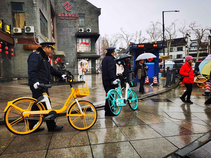 城管隊員將隨意停放的共享單車統一擺放整齊。南京城管供圖