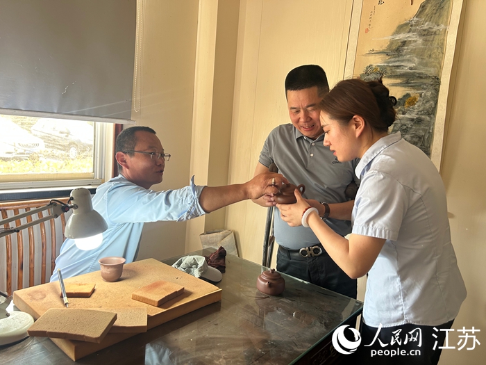 馬偉忠（中）與紫砂工藝師（左）交流作品設計思路。人民網 王丹丹攝
