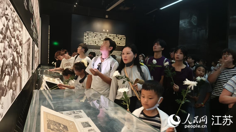 人们手持菊花参观“南京大屠杀史实展”。人民网 王丹丹摄