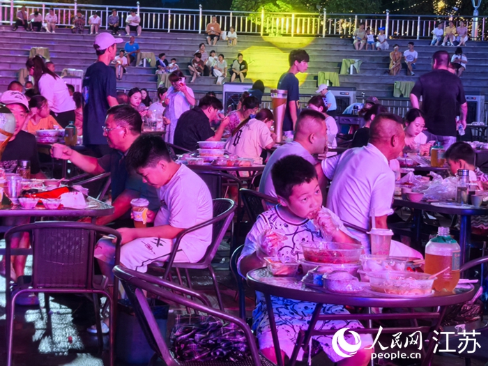 外地游客在兴化市乌巾荡湿地公园品虾看“苏超”直播。人民网 王丹丹摄