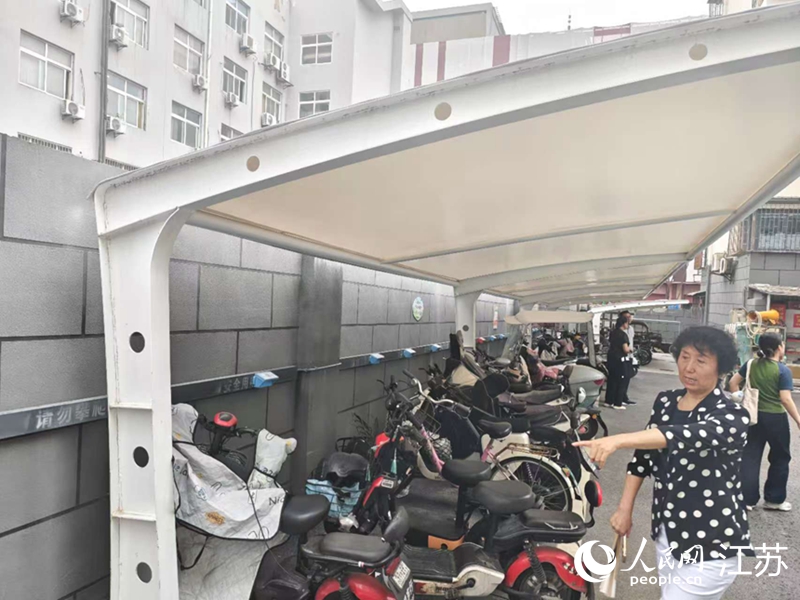 王立華為記者展示小區內新增的車棚和充電樁。