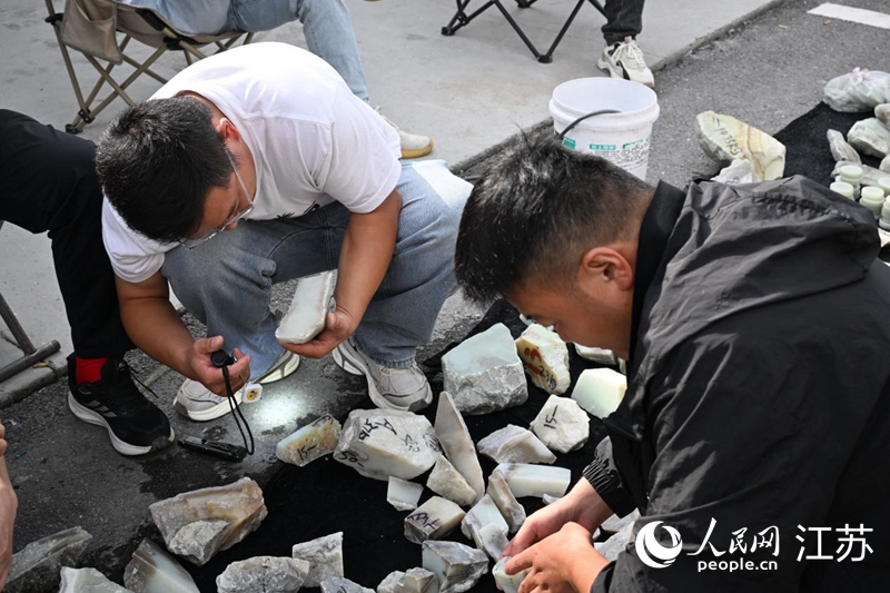 玉石原石交易區，玉石買家正在查看玉石質量。人民網記者張瀚天攝