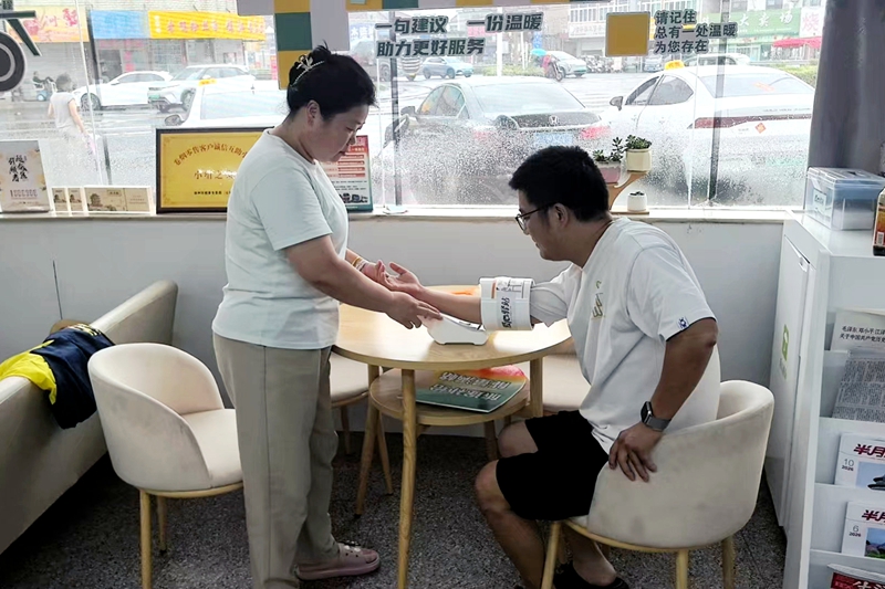 店主潘玉芬为途经司机量血压。杨秀丽摄