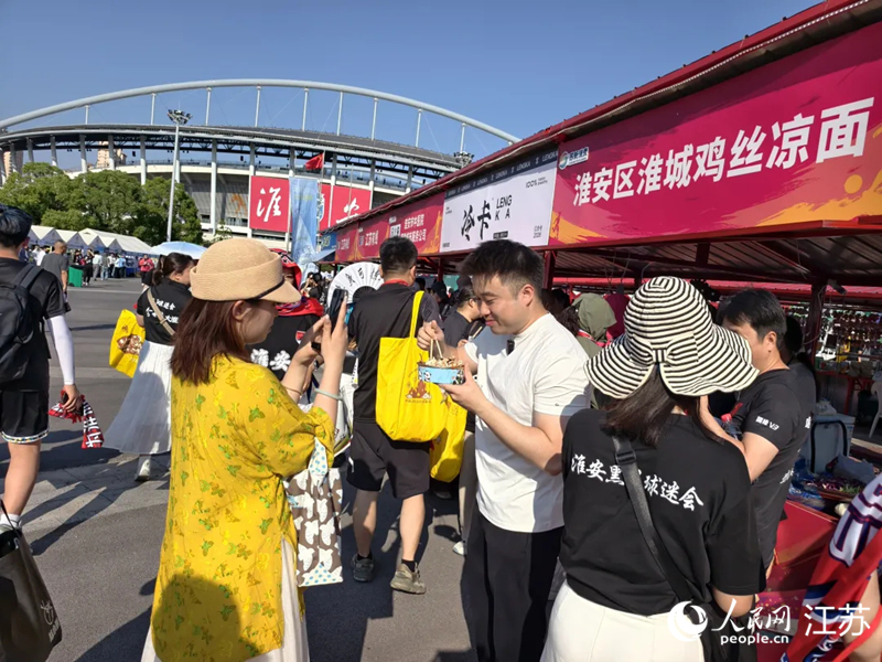 “苏超”赛场旁,不少游客品尝淮安美食。人民网 江楠摄
