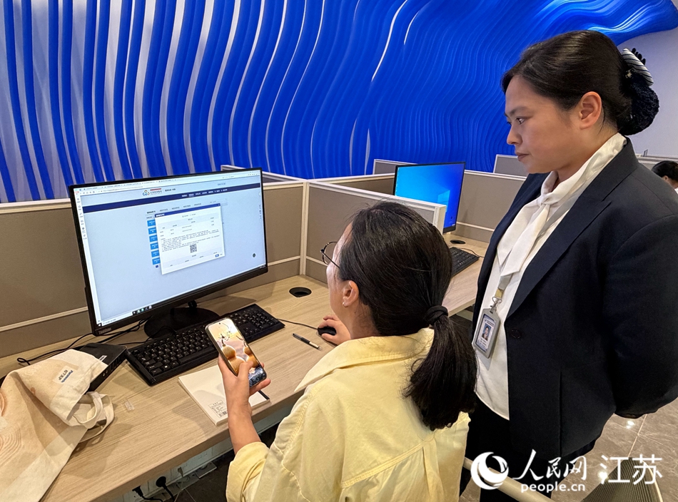 工作人員指導企業辦事人員(右)使用“e啟辦”辦理事項。人民網記者 王繼亮攝
