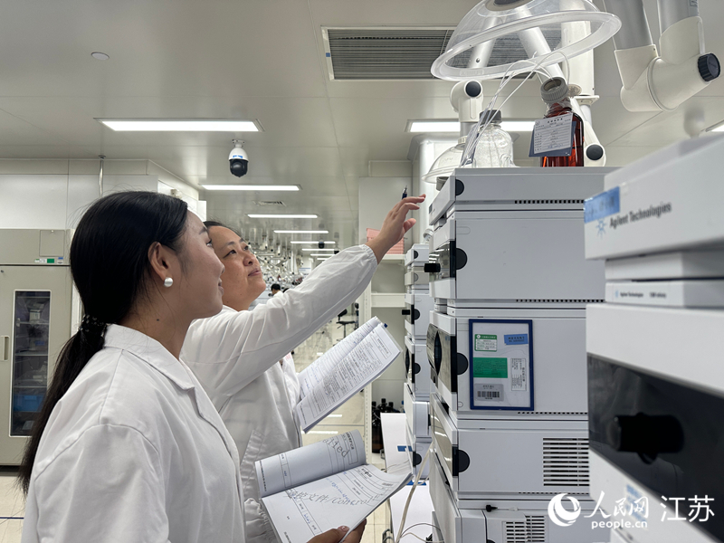 扬子江药业集团质检实验室里,胡婷婷跟同事查看仪器分析数据。人民网 赵登岩摄