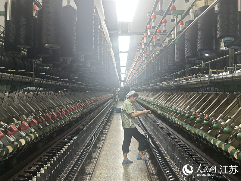 箭鹿集团纺织车间内，一名挡车工正在机器前巡检纱线。人民网 赵登岩摄