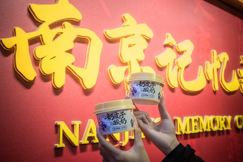 游客手持鹽水鴨風味奶皮子酸奶在南京地標拍照打卡。衛崗乳業供圖