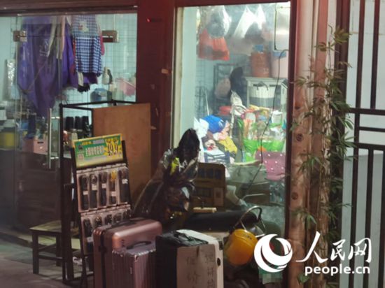 南宁“城中村”一裁缝铺老板将电线从店内拉出为电动自行车充电。人民网 覃心摄