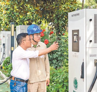 江蘇無錫宜興市白塔村集中充電站，新能源汽車車主（左）在工作人員指導下掃碼向電網反向放電。許 陽攝（人民視覺）