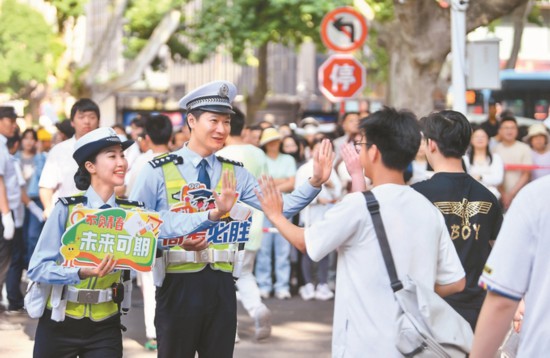 六月六日，南京交警玄武区大队、鼓楼区大队民警值守金陵中学新街口校区，保障考生查看考场时周边交通井然有序。图为民警手持鼓励提示牌，与考生击掌，送上暖心鼓励。 本报记者 范俊彦 摄